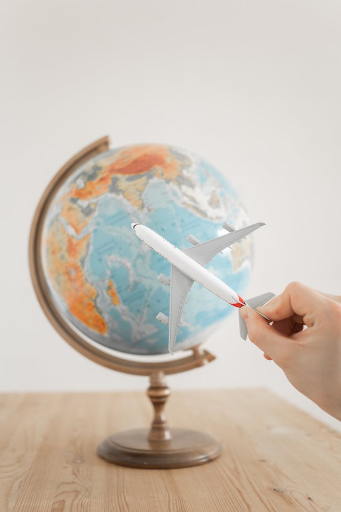 Home Close-up of a hand with a toy airplane in front of a globe, symbolizing travel and exploration.